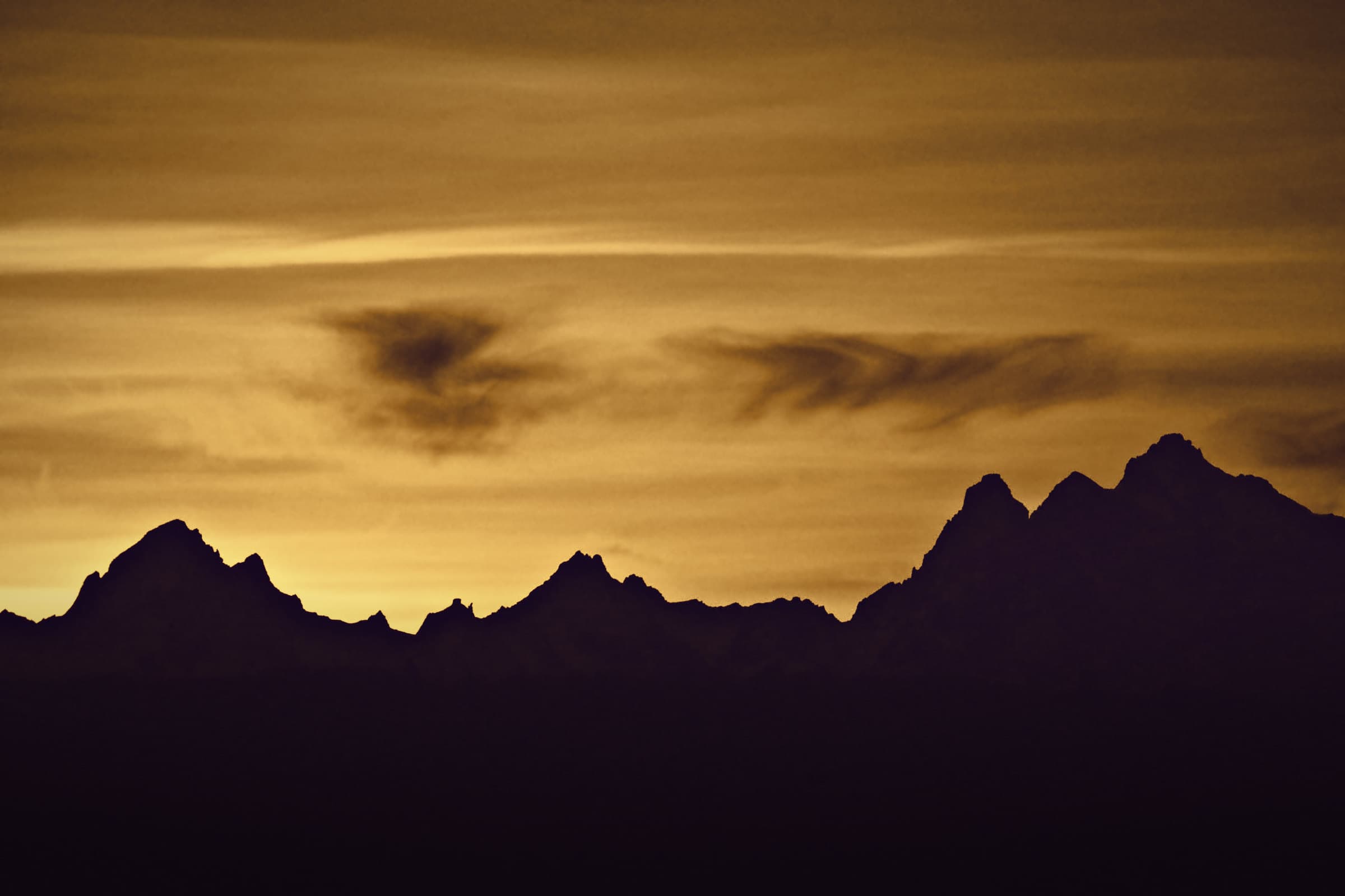 Jagged mountain peaks in silhouette against a golden sky.