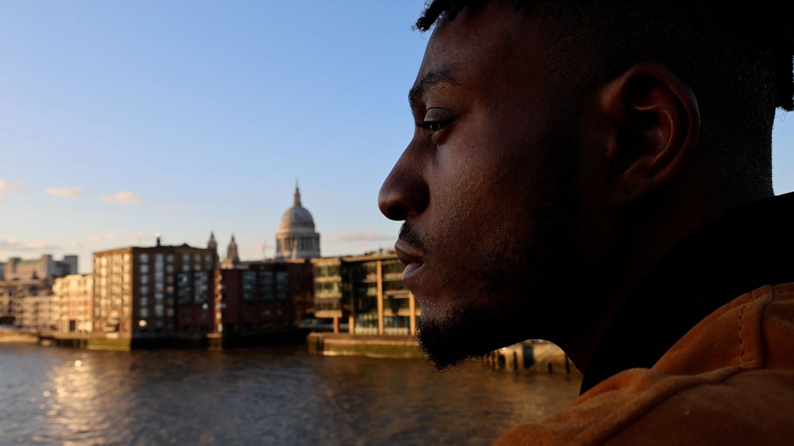 Side profile of Mike O looking out across the River Thames, with St Paul's Cathedral behind him in evening light.